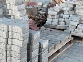 Stacks of concrete and brick blocks arranged neatly at a construction site in bright daylight, showcasing building materials for projects photo