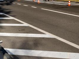 Workers are applying new white paint to street markings, with traffic cones set up to guide vehicles while ensuring safety photo