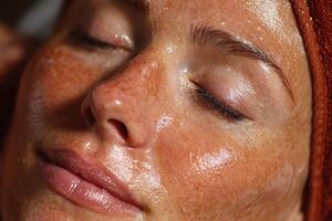 A woman with freckles on her face getting a facial photo