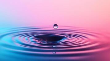 A single water droplet falls into a calm body of water, creating ripples that expand outward photo