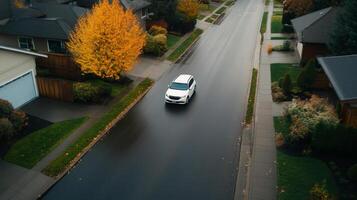 Fall foliage colors complement a car driving on a wet suburban street surrounding homes in a quiet neighborhood during autumn photo