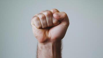 Fist raised with determination against a neutral background expressing strength and resolve in a motivational context photo