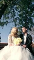 On a bench in a park, the groom and bride are sitting together. It is a beautiful autumn morning at Autumn Park. video