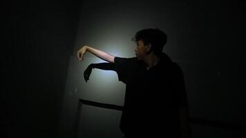 Person Stretching Leg Against Wall in Dim Light video