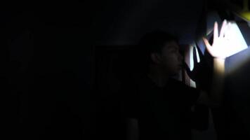 A person standing in a dimly lit space, using a flashlight to illuminate the area. The light creates a dramatic contrast against the dark surroundings, suggesting a sense of mystery or suspense. video