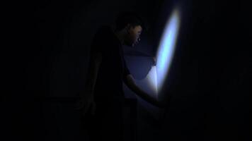 A silhouette of a person standing against a dark background, illuminated by a narrow beam of light. The figure appears to be reaching out or touching a surface, creating a sense of mystery video