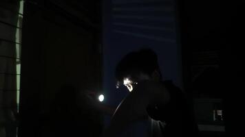 A person standing in a dimly lit hallway, holding a flashlight that illuminates their face. The shadows create a mysterious atmosphere, enhancing the sense of intrigue. video