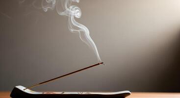 An incense stick is sitting on top of a wooden table photo
