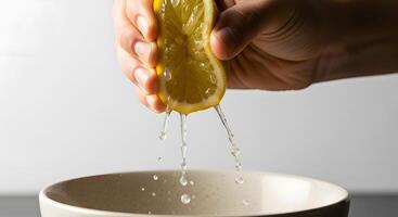 A person holding a lemon slice over a bowl photo