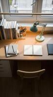 A desk with a lamp, notebook, and a chair photo