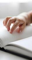 A person's hand is holding an open book photo