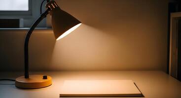 A desk lamp is on a table next to a notebook photo