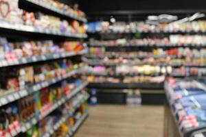Blurred photo of racks of goods and freezers in a small grocery store
