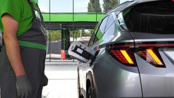 Fuel Station Assistant Near A Vehicle With Opened Fuel Tank Hatch Is Preparing To Refuel photo