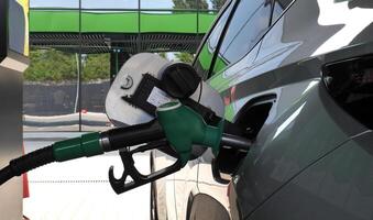 Refueling nozzle inserted into the car gas tank neck rear view photo