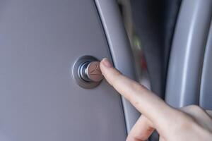 Close-up of a finger pressing a stylish silver button marked with a hanger icon, providing a coat rack or personal storage solution for travelers photo