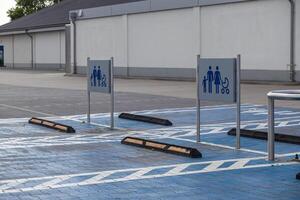 Spacious designated parking spots with blue ground markings and family stroller signs at an empty commercial supermarket lot, symbolizing convenient accessibility photo