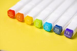 A vibrant row of white art markers with colorful caps displaying numbers like 11 Vermilion, 23 Orange, 34 Yellow, and 59 Dark Green, symbolizing precision art and design photo