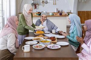 Middle eastern muslim housewife woman in hijab is serving naan bread to family dining table with her husband and relatives during Eid Mubarak, Ramadan festival for feast and gathering photo