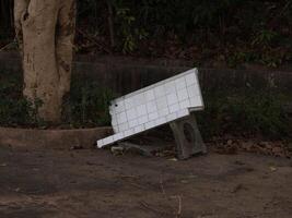 A weathered bench on a neglected sidewalk, highlighting themes of abandonment and decay photo