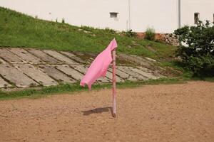 A striking Pink Flag placed on a Sandy Ground surrounded by the beauty of Nature photo