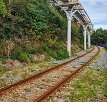 Curving Railroad Tracks Through Greenery with Overhead Structure photo