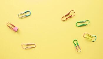 Colorful Paper Clips on Yellow Background Flat Lay photo
