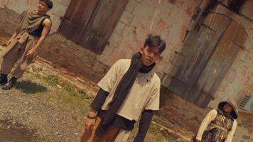 A group of young men dressed in casual, urban clothing, standing in front of a weathered building. The scene has a gritty, artistic vibe with a focus on fashion and expression. video