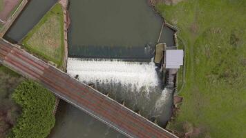 FPV drone footage flying over river weir and fish ladder at hydroelectric site England spring video