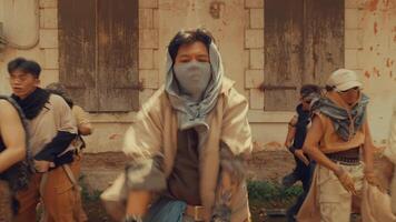 A group of dancers performing a choreographed routine outdoors in an urban setting. They wear casual, rugged clothing and exhibit dynamic movements, showcasing energy and teamwork. video