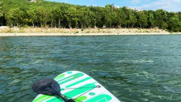 Paddleboard on calm water with mountains, surrounded by lush hills and clear blue sky, showcasing serene outdoor adventure and nature exploration. Sup board. video