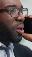 Close up annoyed irritated furious African American business man talking mobile phone shouting yelling problem arguing looking at window in office trouble angry businessman male stress communication video