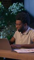 African American business man architect designer working design project measure ruler draft on desk board blueprint architecture plan in night evening office ethnic businessman male guy online laptop video