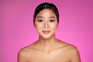Innovative facial mapping on a model in a studio with vibrant pink background showcasing advanced technology photo