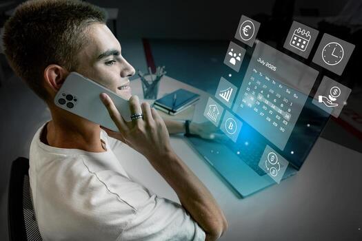 Young professional using smartphone while working on laptop at desk displaying smart technology in modern office space photo