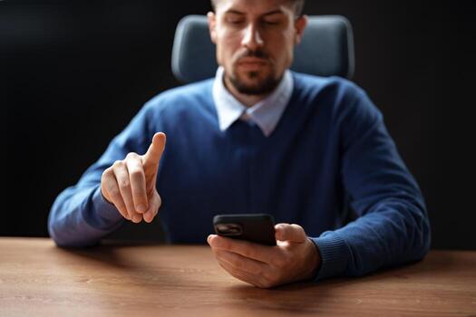 Man using smartphone while gesturing with his hand in a modern office setting during the day photo