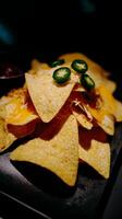 Delicious Nachos with Melted Cheese and Jalapenos on Dark Background. photo