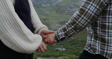Two people holding hands in front of a mountain photo