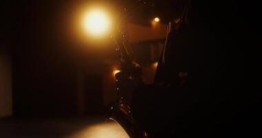 A person playing a saxophone in a dark room photo