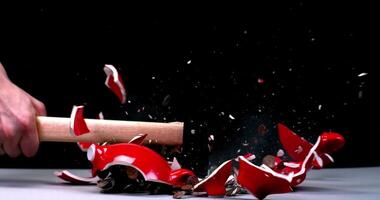 A person is smashing a red object with a wooden stick photo