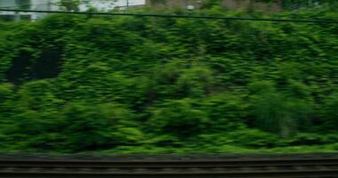 A train traveling through a city with a green wall video