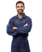 A smiling man in blue work overalls with arms crossed standing against a white background photo