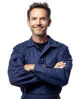 Portrait of a smiling man in blue work overalls with arms crossed against white background photo