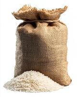 A jute sack filled with rice standing next to a pile of uncooked rice on a white background photo