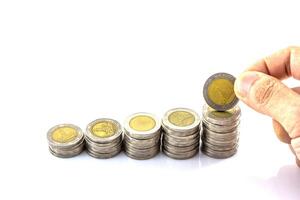 A hand is holding a stack of coins with a coin on top photo
