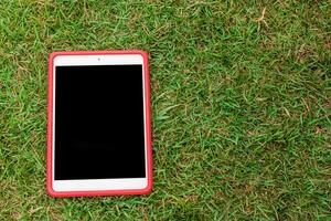 A red tablet computer is sitting on the grass photo