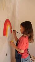 vertical Young girl painting rainbow on wall with brush and tempera colors video