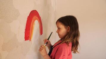 Young girl painting rainbow on wall with brush and tempera colors video