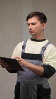 A man in overalls holding a tablet computer video