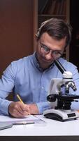 vertical Frustrated scientist throwing paper ball near microscope in home office at night video